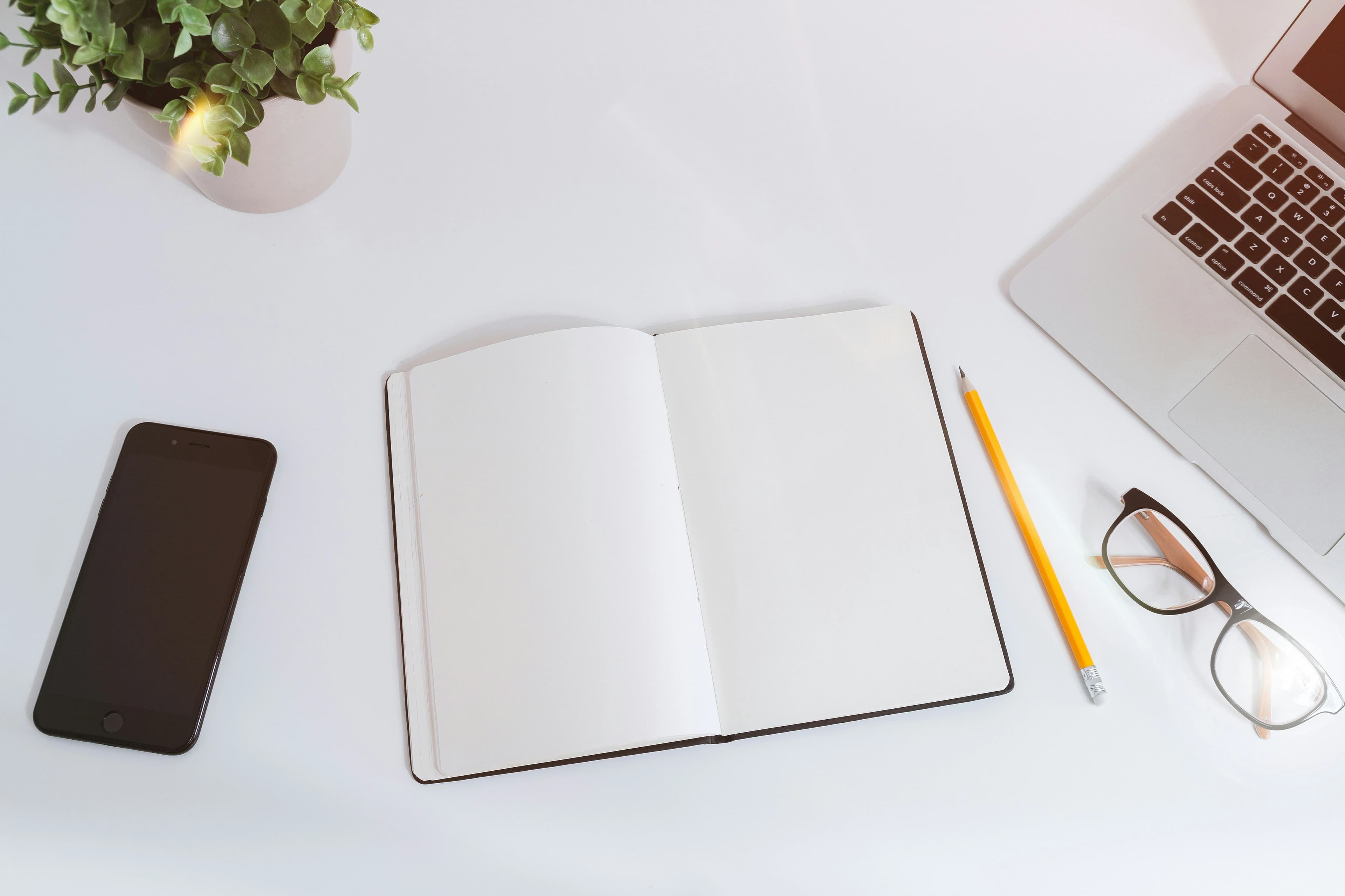 Laptop beside an open notebook on a workspace.