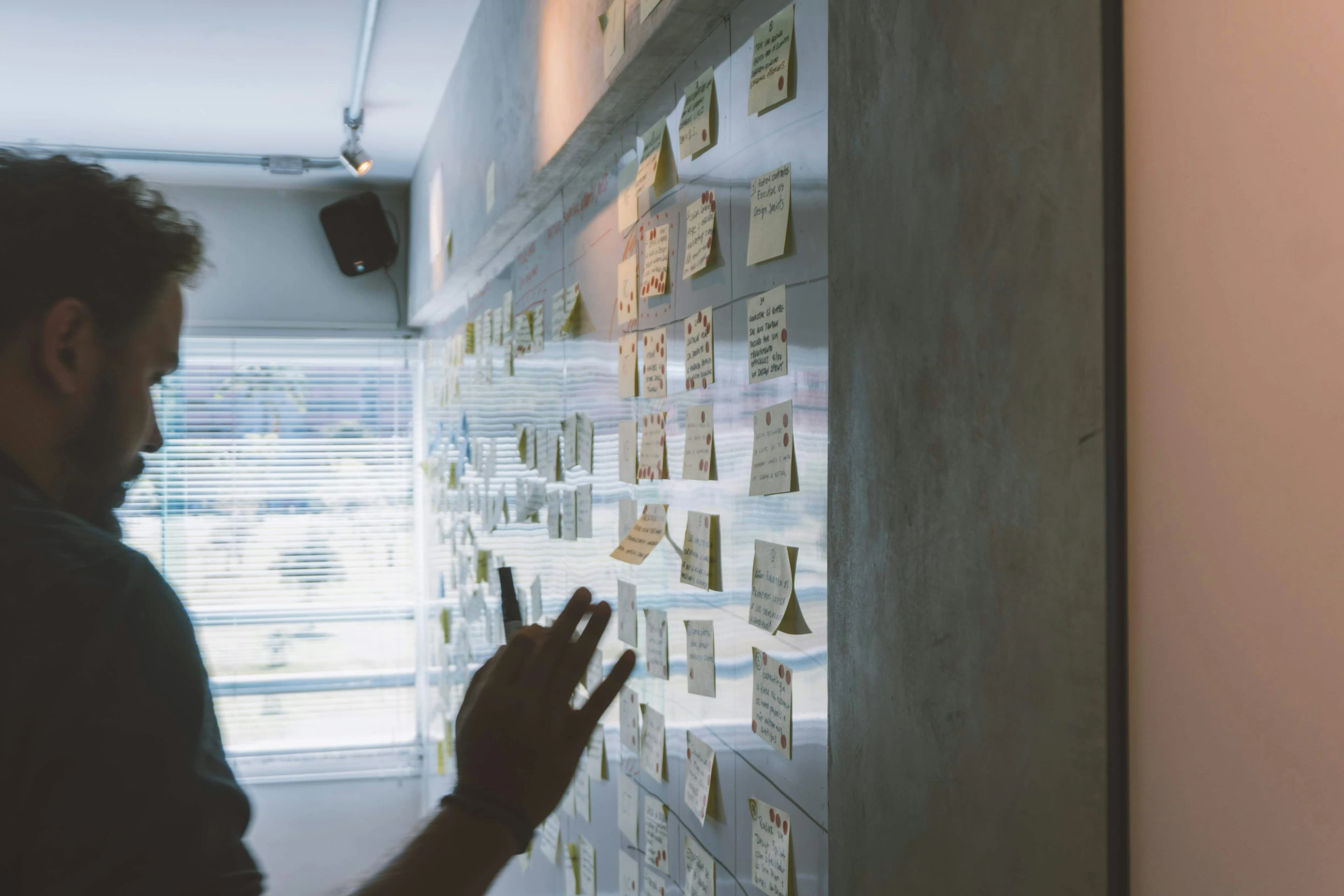 Designer organizing interface audit notes on a wall.