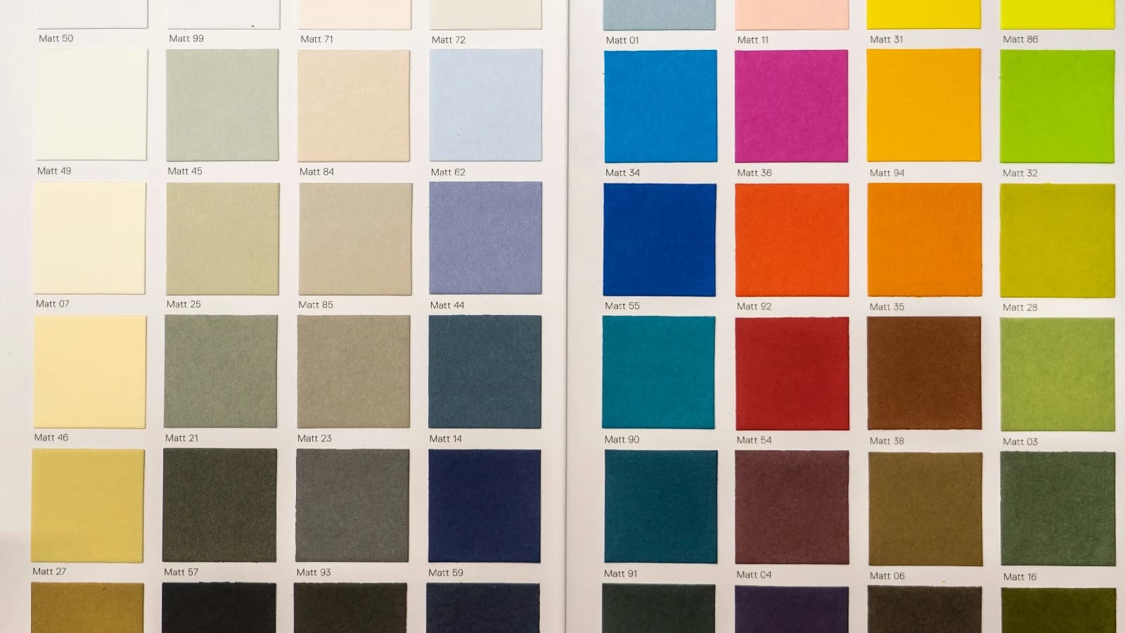 Open colour-swatch book displaying neutral and bright sample squares in a grid.