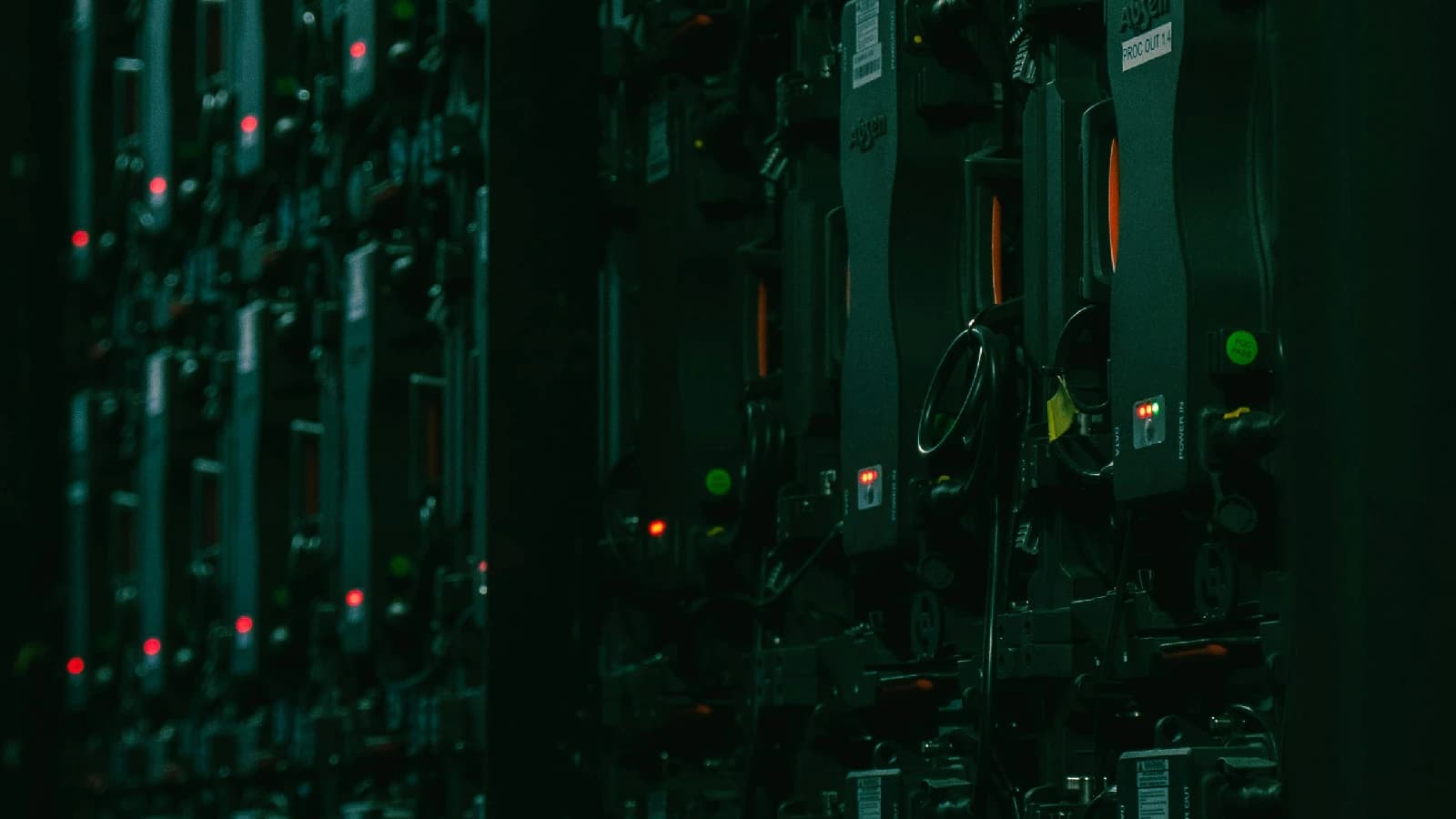 Rows of server racks with red and green status lights in a dark data centre.